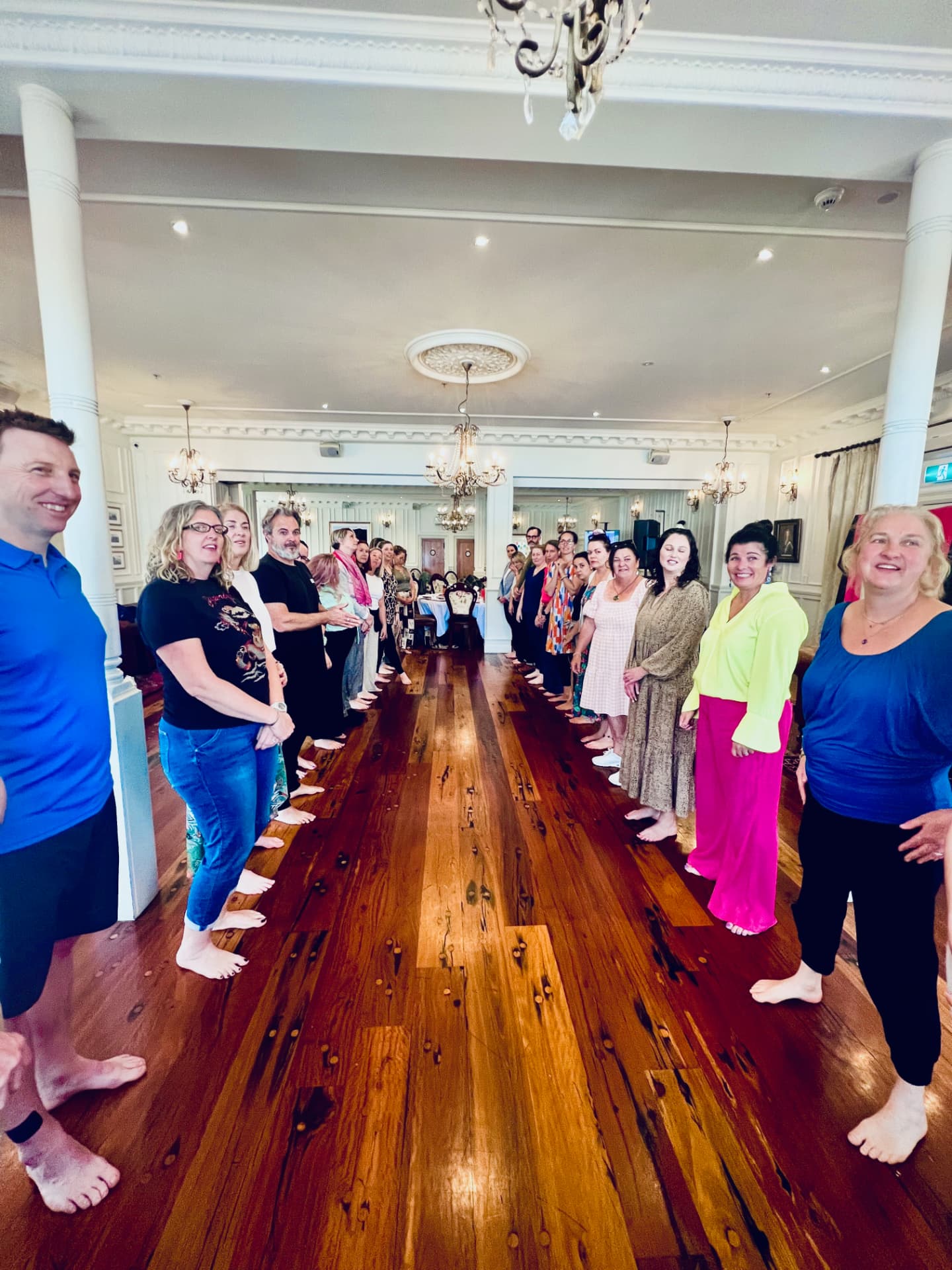 Retreat guests standing barefoot in two long lines in the Russell ballroom