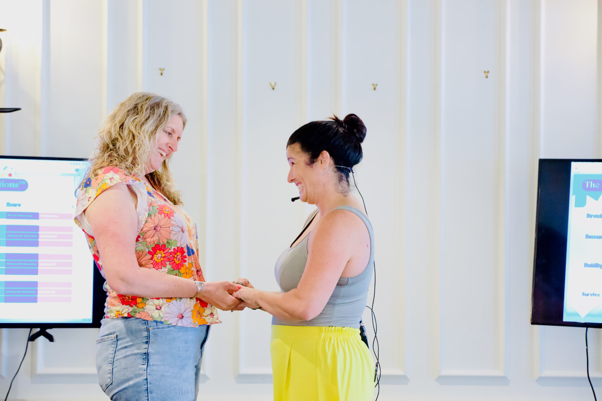 Sarah holding hands with an attendee in front of the workshop screens