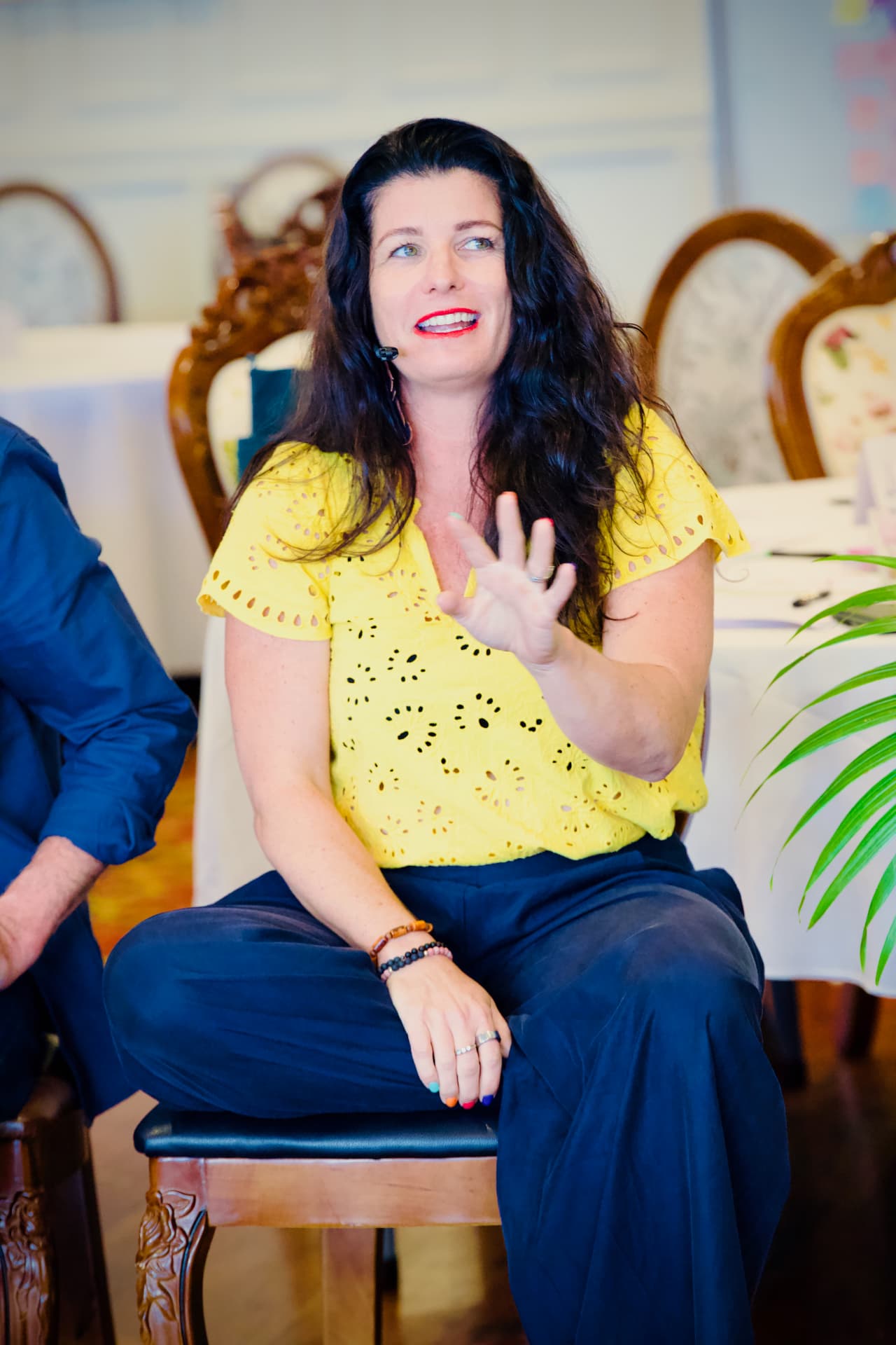 Sarah Greener seated with a headset microphone, mid-sentence while presenting