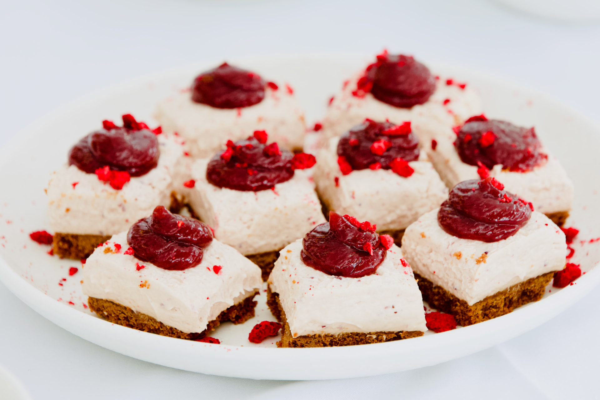 Plate of cheesecake squares topped with berry compote