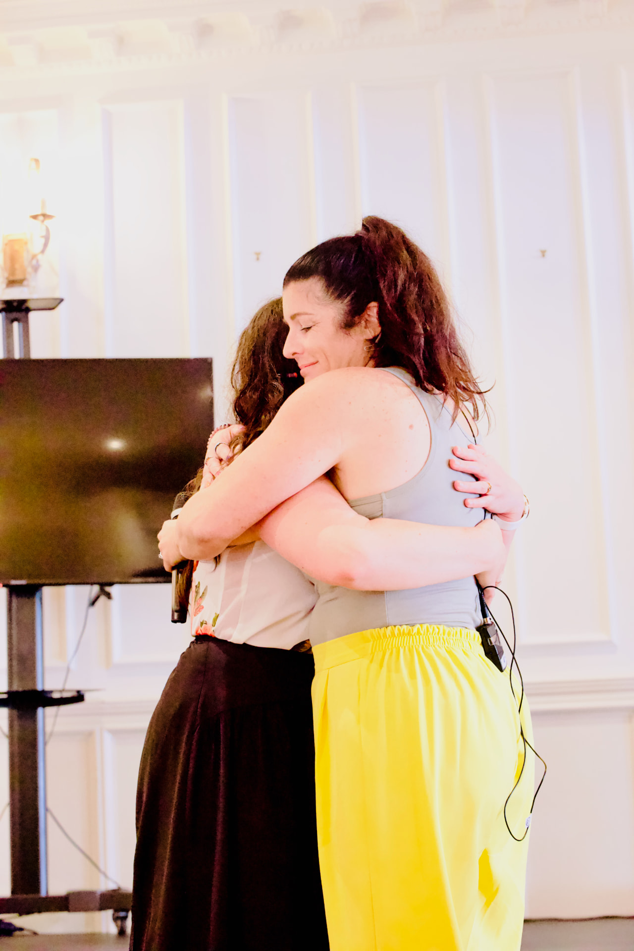 Two women embracing on stage after a guest speaker session at the Season 26 retreat